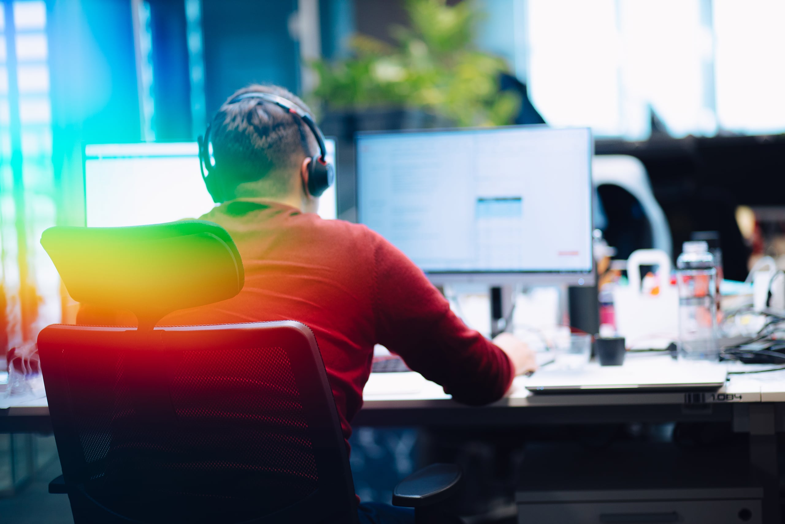 a man wearing headphones sitting at a desk with a computer