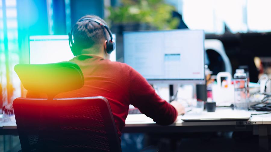 a man wearing headphones sitting at a desk with a computer
